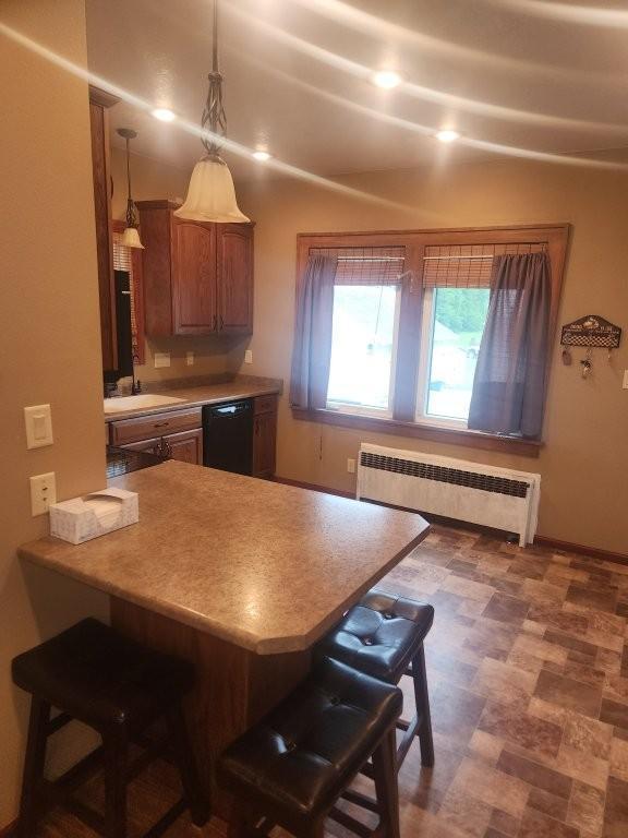 313 2nd St, Hills, MN 56138 - kitchen with radiator, black dishwasher, a breakfast bar, a sink, and brown cabinetry