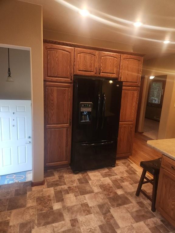 313 2nd St, Hills, MN 56138 - kitchen featuring black fridge with ice dispenser and brown cabinets