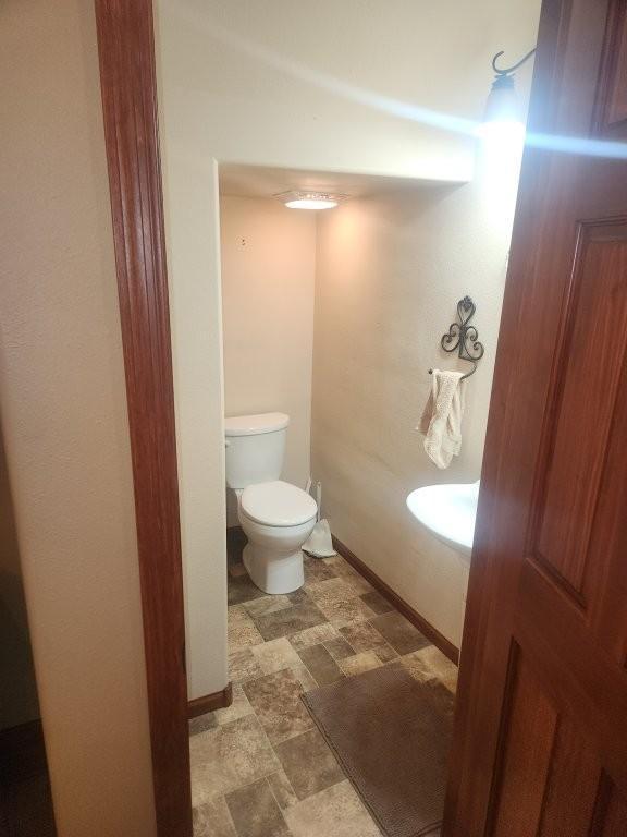 313 2nd St, Hills, MN 56138 - bathroom featuring toilet, stone finish floors, and baseboards