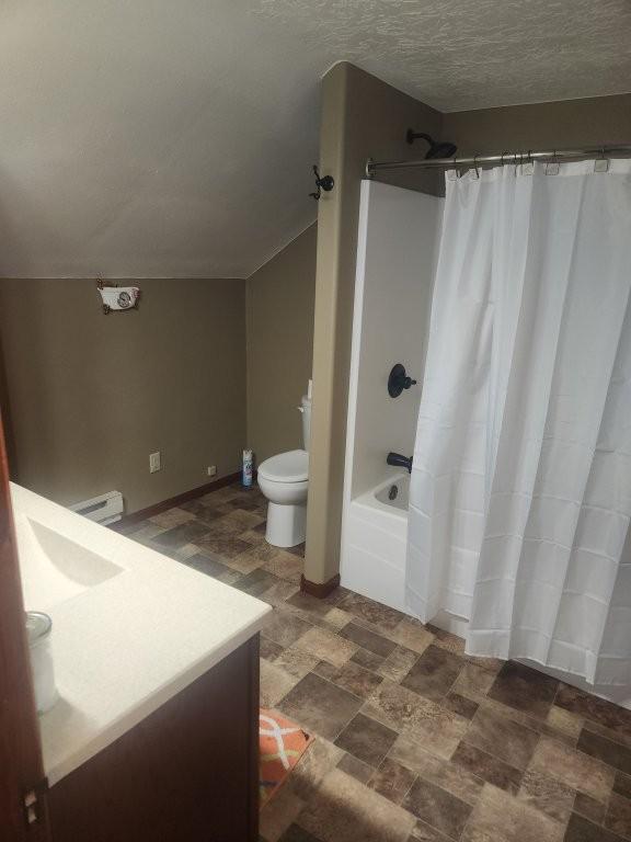 313 2nd St, Hills, MN 56138 - full bath with vanity, toilet, shower / tub combo, a baseboard heating unit, and baseboards