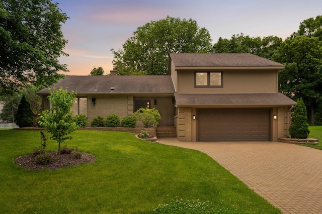 2367 Apache Ct, Mendota Heights, MN 55120 - tri-level home featuring an attached garage, decorative driveway, brick siding, a yard, and a chimney