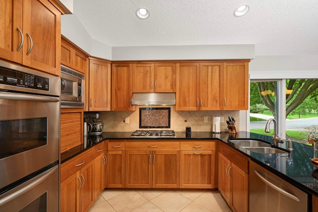 2367 Apache Ct, Mendota Heights, MN 55120 - kitchen with appliances with stainless steel finishes, brown cabinetry, under cabinet range hood, decorative backsplash, and a textured ceiling
