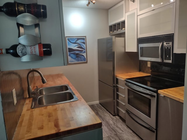433 7th St Unit 1603, Minneapolis, MN 55415 - kitchen featuring butcher block countertops, stainless steel appliances, wood finished floors, and white cabinets