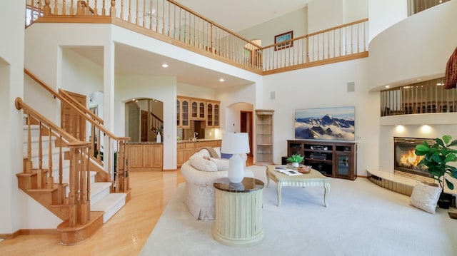 E5110 Interlachen Blvd, Pleasant Valley Twp, WI 54738 - living room with a towering ceiling, arched walkways, a glass covered fireplace, stairway, and light wood-style floors