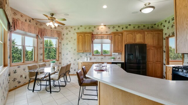 E5110 Interlachen Blvd, Pleasant Valley Twp, WI 54738 - kitchen featuring black refrigerator with ice dispenser, wallpapered walls, light countertops, baseboards, and ceiling fan