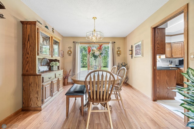 5701 33rd St S, Fargo, ND 58104 - dining space featuring light wood-style floors, a chandelier, baseboards, and a textured ceiling