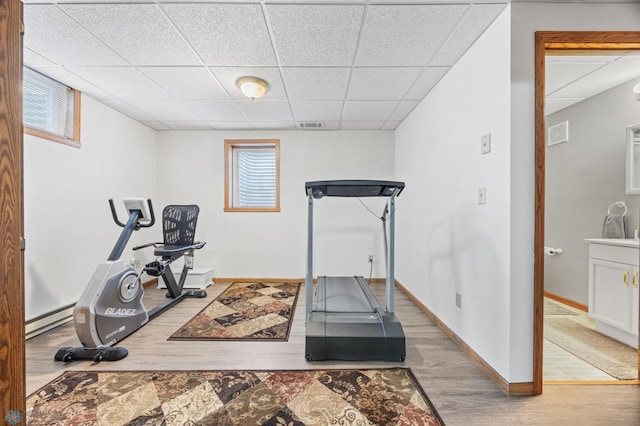 5701 33rd St S, Fargo, ND 58104 - exercise room featuring a paneled ceiling, wood finished floors, baseboards, and a baseboard radiator