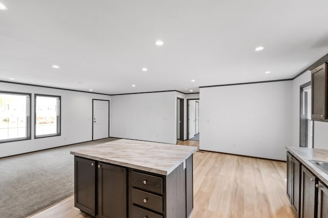 215 Mckay Ave # 42, Alexandria, MN 56308 - kitchen with dark brown cabinets, open floor plan, light countertops, recessed lighting, and ornamental molding