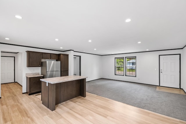 215 Mckay Ave # 42, Alexandria, MN 56308 - kitchen featuring freestanding refrigerator, dark brown cabinets, light countertops, a kitchen island, and recessed lighting