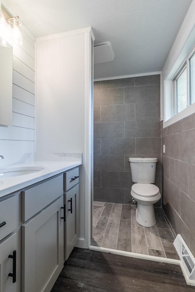 1020 1st St S, Cold Spring, MN 56320 - bathroom featuring vanity, wood finished floors, tile walls, and toilet