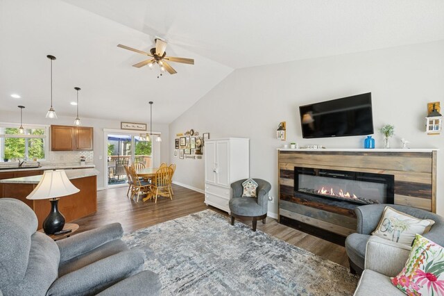 13362 Jefferson St, Becker, MN 55308 - living room featuring dark wood-style flooring, ceiling fan, vaulted ceiling, baseboards, and a glass covered fireplace