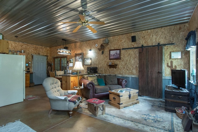 19214 County Road 12, Irondale Twp, MN 56455 - living area with concrete floors, a barn door, a ceiling fan, and a wainscoted wall