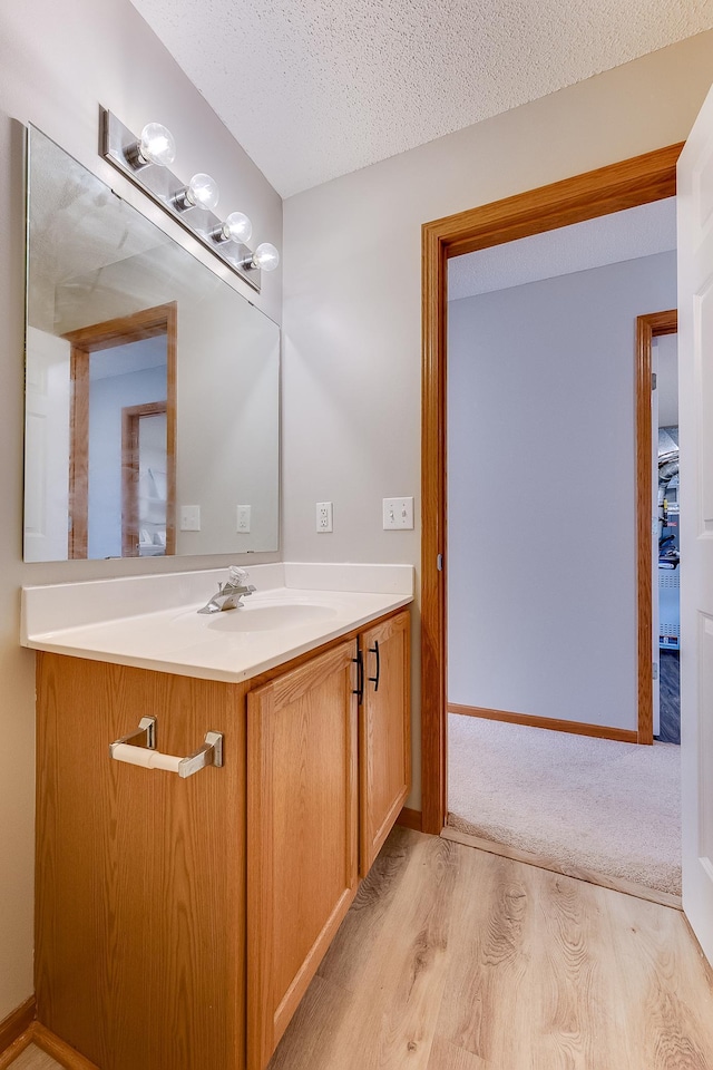 7539 Derby Ln, Shakopee, MN 55379 - bathroom with wood finished floors, vanity, a textured ceiling, and baseboards