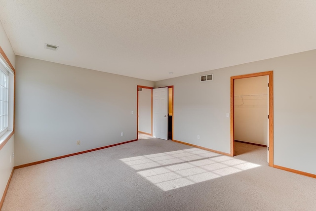 7539 Derby Ln, Shakopee, MN 55379 - unfurnished bedroom with light carpet, a spacious closet, baseboards, and a textured ceiling