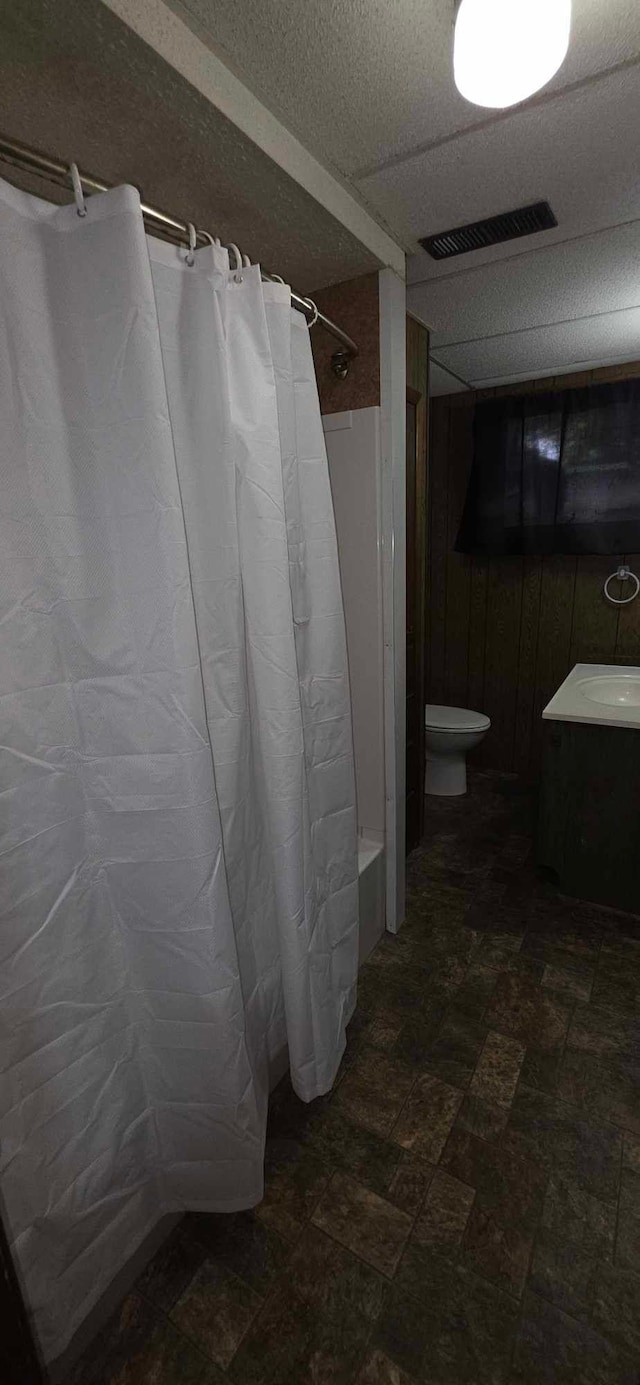 17548 749th Ave, Albert Lea Twp, MN 56007 - full bath with toilet, wooden walls, shower / bath combo with shower curtain, and vanity