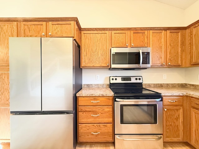 3100 212th St W, Farmington, MN 55024 - kitchen featuring appliances with stainless steel finishes, light countertops, lofted ceiling, and brown cabinets