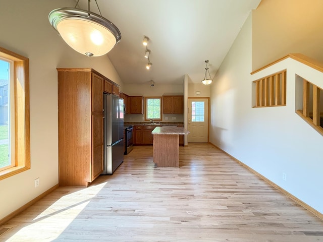 3100 212th St W, Farmington, MN 55024 - kitchen featuring stainless steel appliances, lofted ceiling, light wood-type flooring, hanging light fixtures, and brown cabinetry
