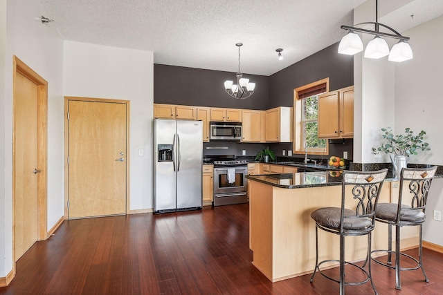 3310 Nicollet Ave Unit 302, Minneapolis, MN 55408 - kitchen with appliances with stainless steel finishes, a peninsula, dark wood finished floors, light brown cabinets, and hanging light fixtures