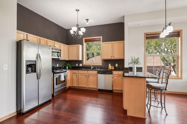 3310 Nicollet Ave Unit 302, Minneapolis, MN 55408 - kitchen with stainless steel appliances, light brown cabinets, a peninsula, a sink, and a chandelier