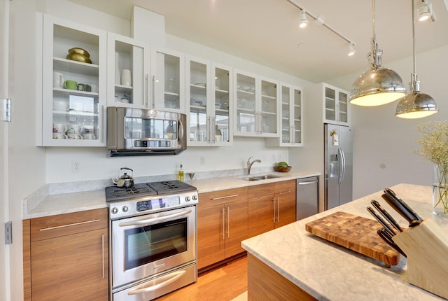 901 2nd St Unit 905, Minneapolis, MN 55415 - kitchen with stainless steel appliances, brown cabinets, a sink, rail lighting, and glass insert cabinets