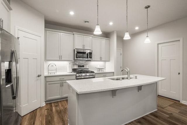 8738 Upper 9th Pl N, Lake Elmo, MN 55042 - kitchen with appliances with stainless steel finishes, a sink, dark wood finished floors, an island with sink, and decorative light fixtures