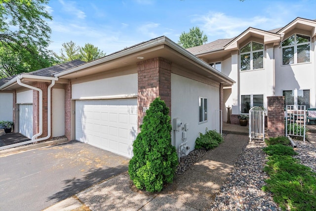 5555 70th St, Edina, MN 55439 - view of side of property with brick siding, a garage, asphalt driveway, and stucco siding