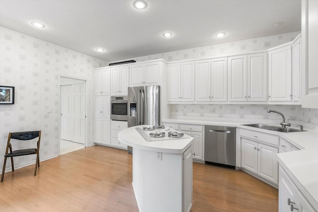 5555 70th St, Edina, MN 55439 - kitchen with appliances with stainless steel finishes, wallpapered walls, a sink, light countertops, and a center island