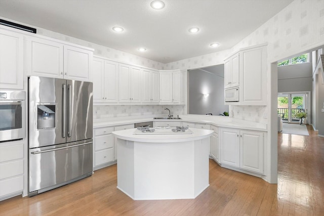 5555 70th St, Edina, MN 55439 - kitchen with stainless steel appliances, light countertops, wallpapered walls, light wood-style flooring, and a sink