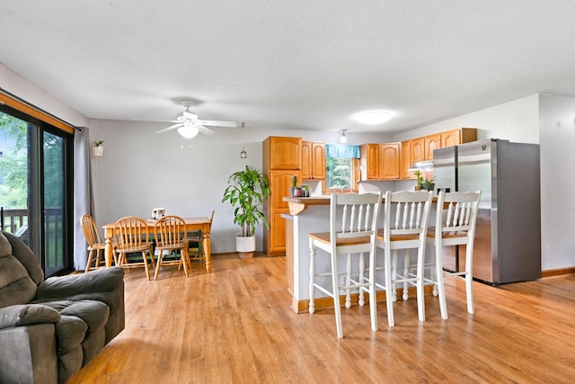 15607 93rd Cir NE, Otsego, MN 55330 - kitchen with freestanding refrigerator, healthy amount of natural light, light wood-type flooring, a breakfast bar area, and a textured ceiling