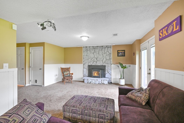 15607 93rd Cir NE, Otsego, MN 55330 - living area featuring wainscoting, a textured ceiling, carpet flooring, and a stone fireplace