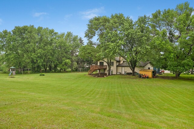 15607 93rd Cir NE, Otsego, MN 55330 - view of green lawn featuring stairs, a playground, a wooden deck, and view of scattered trees