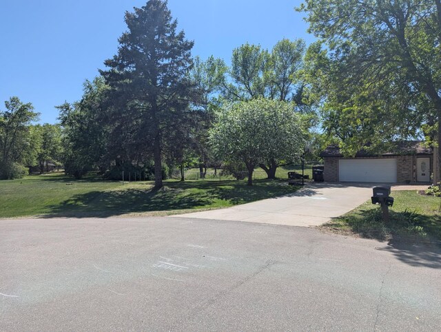 15607 93rd Cir NE, Otsego, MN 55330 - view of property hidden behind natural elements with concrete driveway, a front yard, and an attached garage