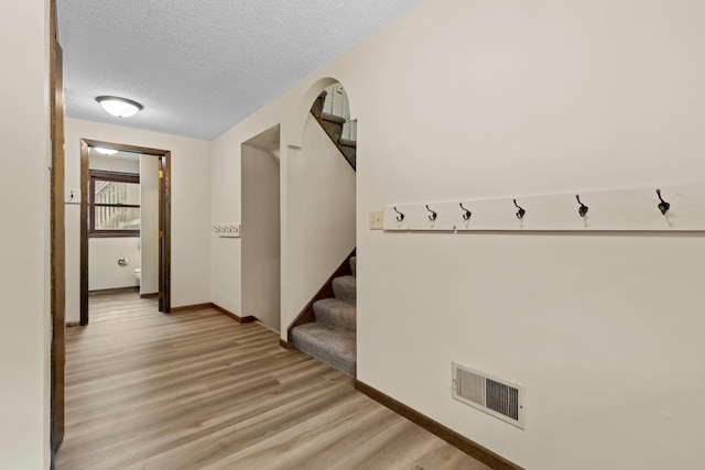 24345 165th St NW, Orrock Twp, MN 55309 - hallway with light wood-style floors, stairs, and a textured ceiling