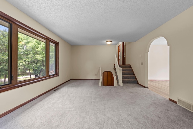 24345 165th St NW, Orrock Twp, MN 55309 - carpeted spare room with healthy amount of natural light, a textured ceiling, arched walkways, and stairs