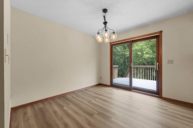 24345 165th St NW, Orrock Twp, MN 55309 - unfurnished room with light wood-style floors, a chandelier, and a textured ceiling