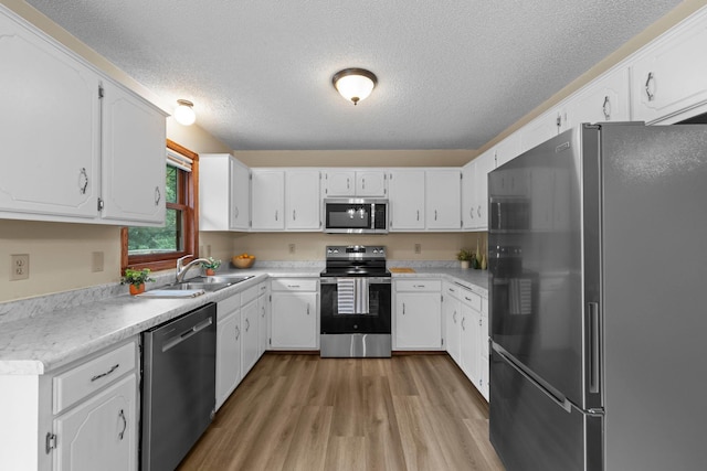 24345 165th St NW, Orrock Twp, MN 55309 - kitchen with stainless steel appliances, a textured ceiling, light wood-style flooring, white cabinets, and light countertops