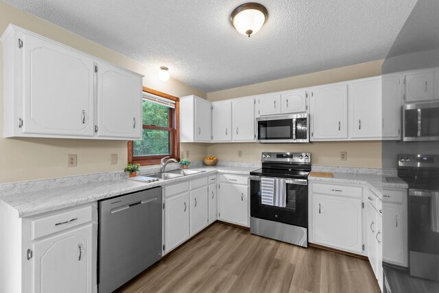 24345 165th St NW, Orrock Twp, MN 55309 - kitchen with stainless steel appliances, a textured ceiling, white cabinetry, light wood-type flooring, and light countertops