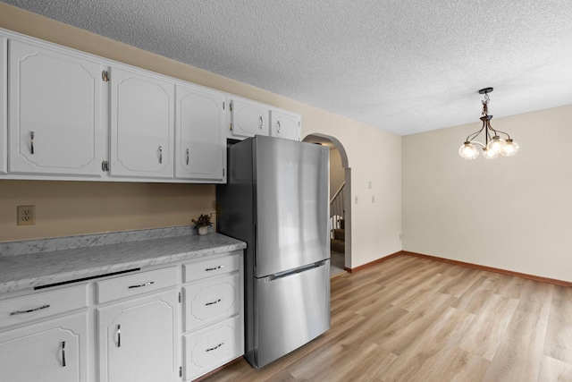 24345 165th St NW, Orrock Twp, MN 55309 - kitchen featuring freestanding refrigerator, a textured ceiling, arched walkways, white cabinetry, and light wood finished floors