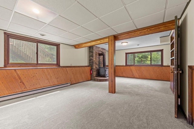 24345 165th St NW, Orrock Twp, MN 55309 - spare room with a wood stove, wooden walls, baseboard heating, carpet floors, and a drop ceiling
