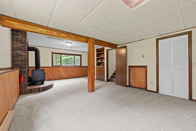 24345 165th St NW, Orrock Twp, MN 55309 - below grade area featuring a wood stove, carpet flooring, wood walls, stairs, and a paneled ceiling