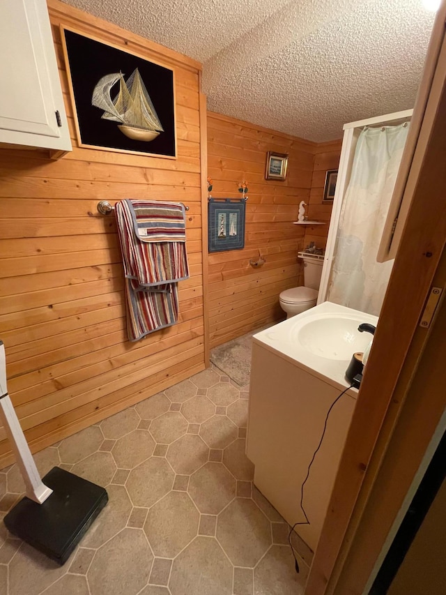 718 22nd St NW, Bemidji, MN 56601 - bathroom with vanity, tile patterned floors, wood walls, a textured ceiling, and toilet