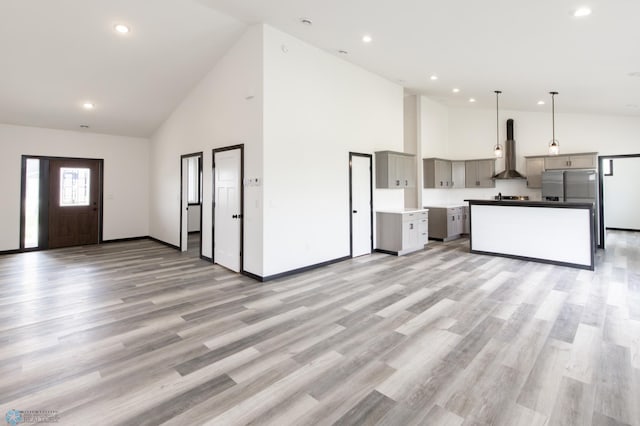 4712 Hampton Loop S, Moorhead, MN 56560 - kitchen featuring wall chimney exhaust hood, high vaulted ceiling, gray cabinetry, open floor plan, and stainless steel fridge