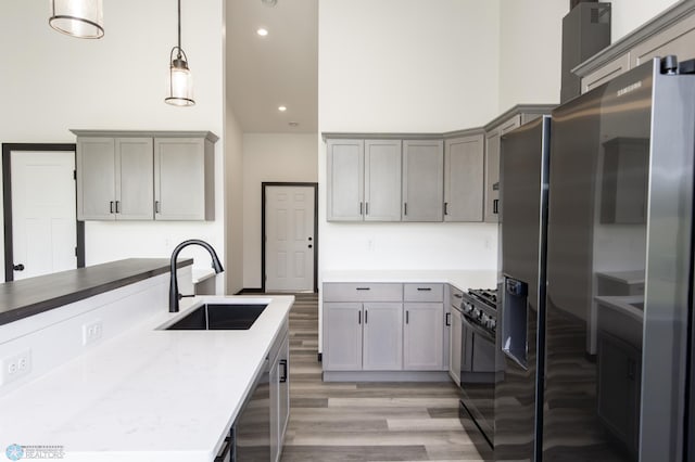 4712 Hampton Loop S, Moorhead, MN 56560 - kitchen featuring a sink, black gas stove, light wood-style flooring, gray cabinets, and a towering ceiling