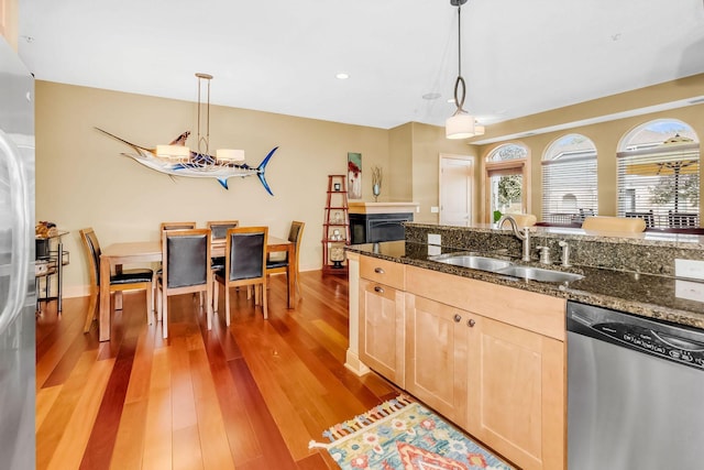 650 Main St N Unit B05, Stillwater, MN 55082 - kitchen featuring appliances with stainless steel finishes, a sink, light brown cabinets, light wood finished floors, and decorative light fixtures