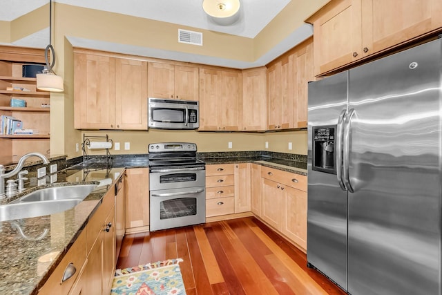 650 Main St N Unit B05, Stillwater, MN 55082 - kitchen featuring appliances with stainless steel finishes, light brown cabinetry, a sink, dark wood-type flooring, and dark stone counters