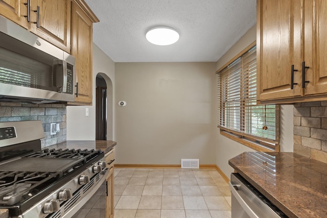 5107 Corvallis Ave N, Crystal, MN 55429 - kitchen with stainless steel appliances, arched walkways, tasteful backsplash, baseboards, and a textured ceiling