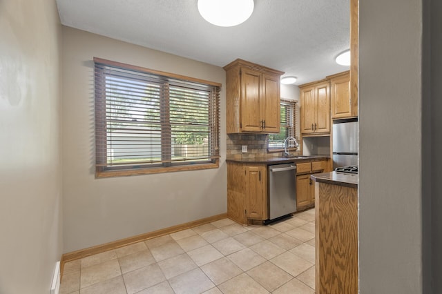 5107 Corvallis Ave N, Crystal, MN 55429 - kitchen with appliances with stainless steel finishes, dark countertops, baseboards, a sink, and a textured ceiling