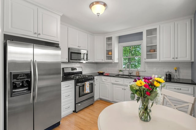 5625 Upton Ave S, Minneapolis, MN 55410 - kitchen with stainless steel appliances, white cabinetry, dark countertops, glass insert cabinets, and tasteful backsplash