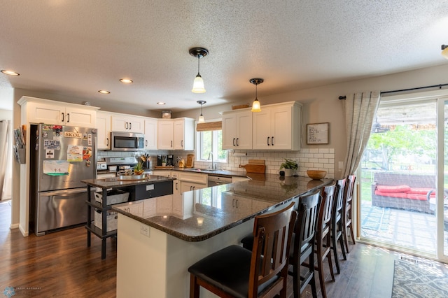 4408 Riverwood Dr N, Fargo, ND 58102 - kitchen featuring stainless steel appliances, a sink, a peninsula, dark wood-style floors, and a textured ceiling