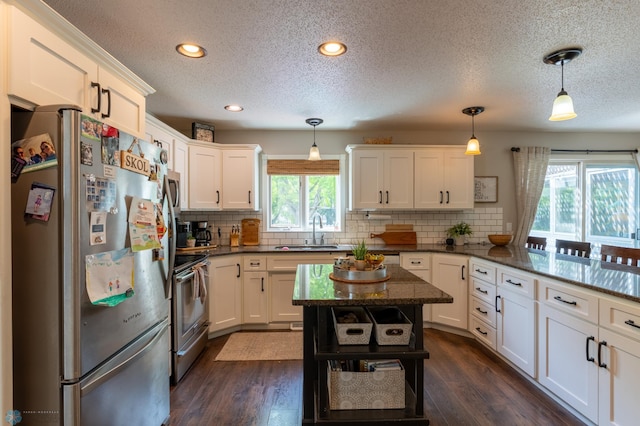 4408 Riverwood Dr N, Fargo, ND 58102 - kitchen with appliances with stainless steel finishes, a sink, a textured ceiling, white cabinets, and tasteful backsplash